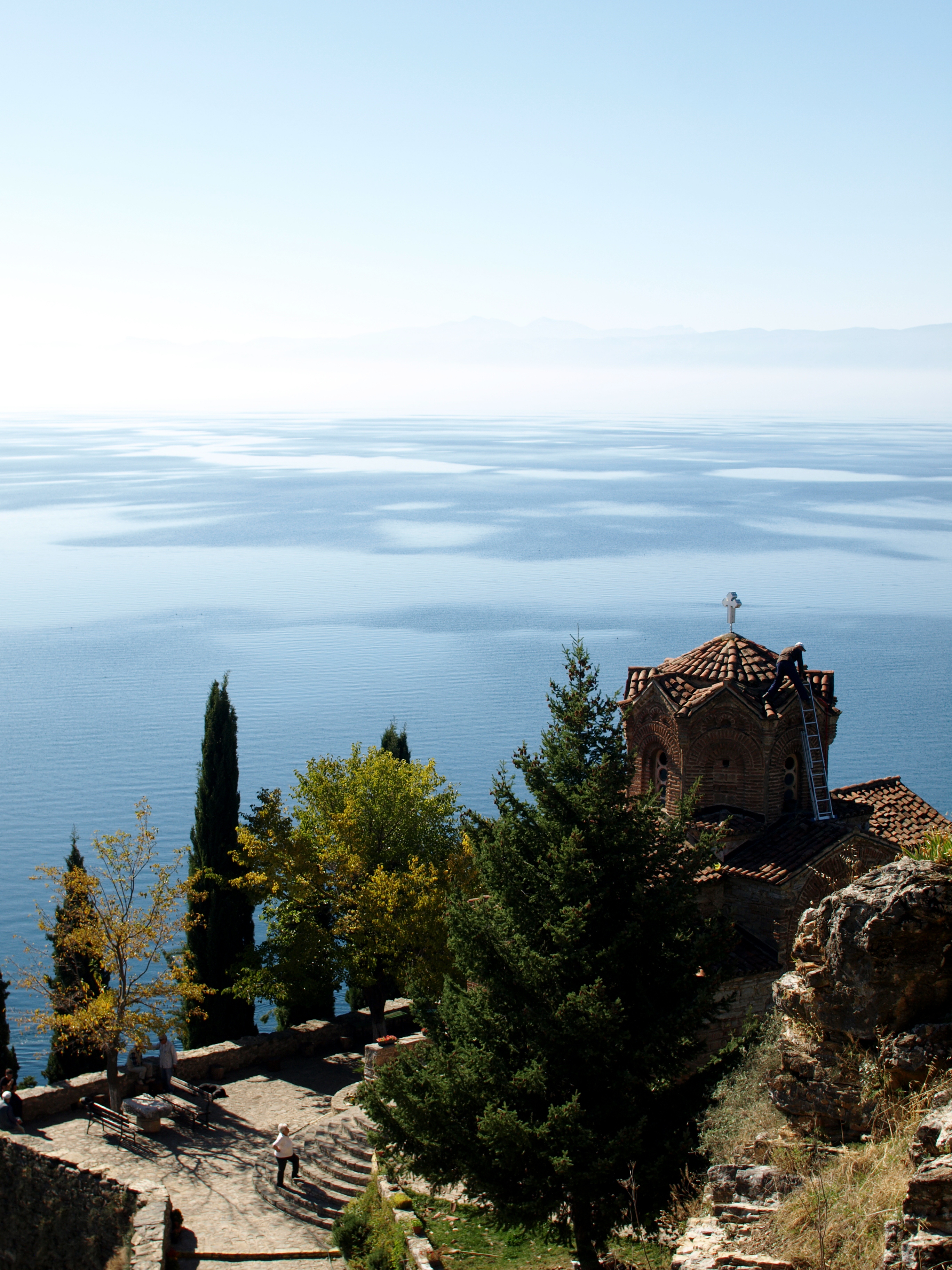 View of Sveti Jovan Kaneo with Lake Ohrid seen in the background. It is empty except for the caretakers repairing the roof.